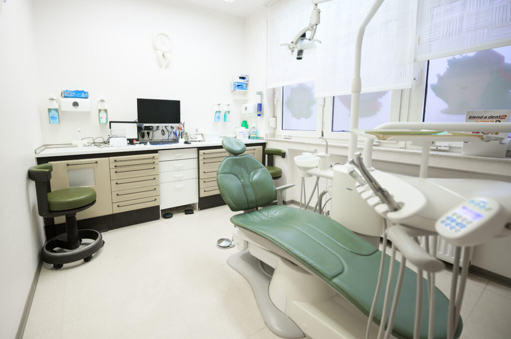 Modernes und helles Behandlungszimmer mit grünem Behandlungsstuhl in der Zahnarztpraxis Amayri