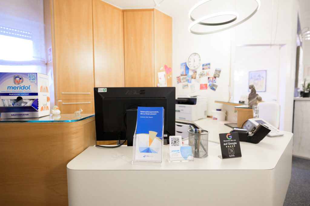 Freundlicher Empfangsbereich mit Anmeldung und Informationsmaterial in der Zahnarztpraxis Amayri