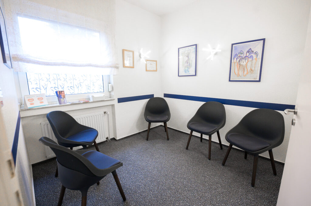 Wartezimmer mit modernen Stühlen und Wanddekoration in der Zahnarztpraxis Amayri in Duisburg
