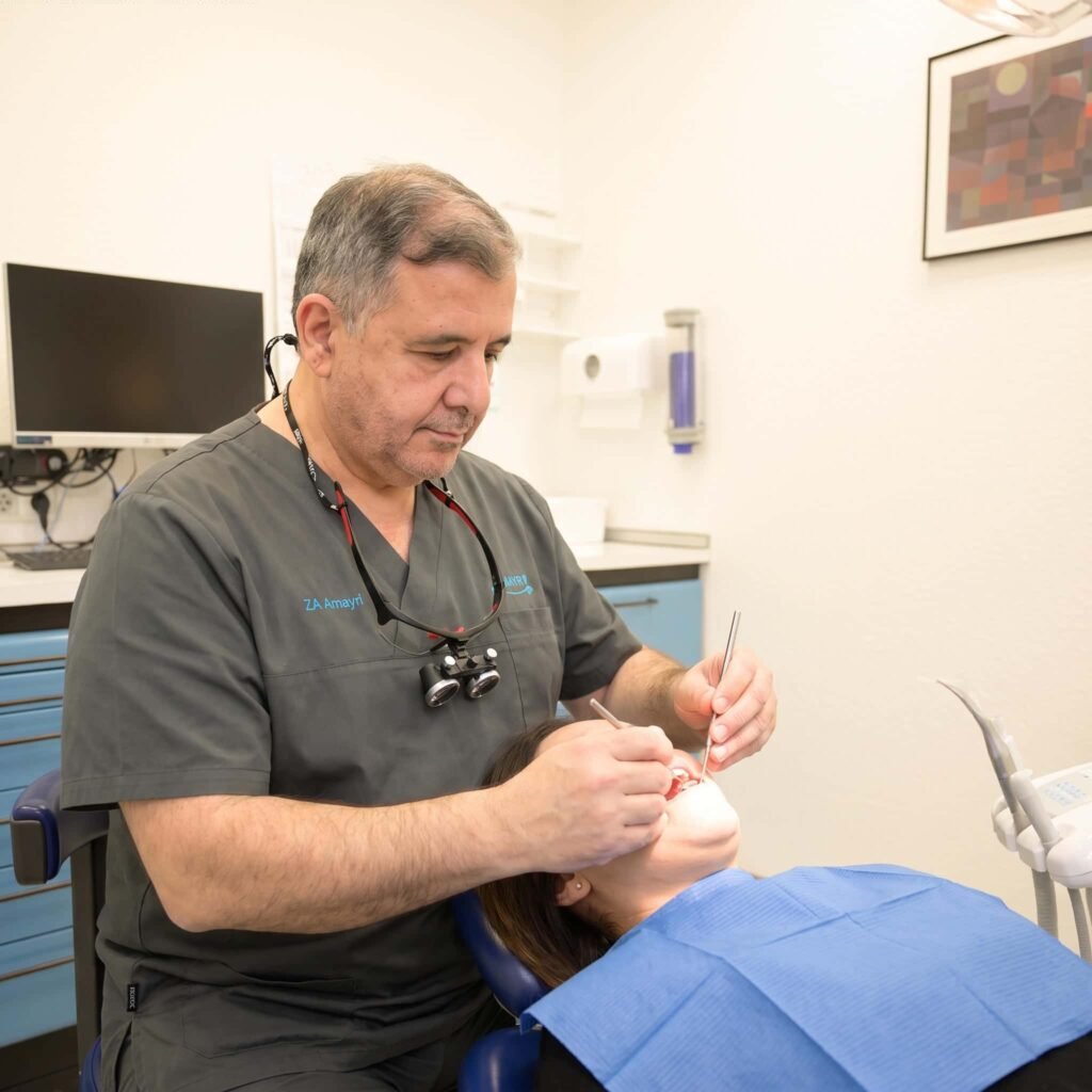 Zahnarzt untersucht den Mund einer liegenden Patientin mit einem Mundspiegel und einem zahnmedizinischen Instrument.